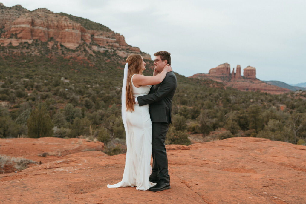 Newlyweds embracing on a red rock plateau during their Sedona micro wedding.