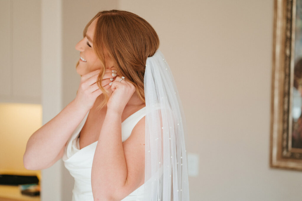 Bride putting on earrings while preparing for her stress-free micro wedding ceremony.